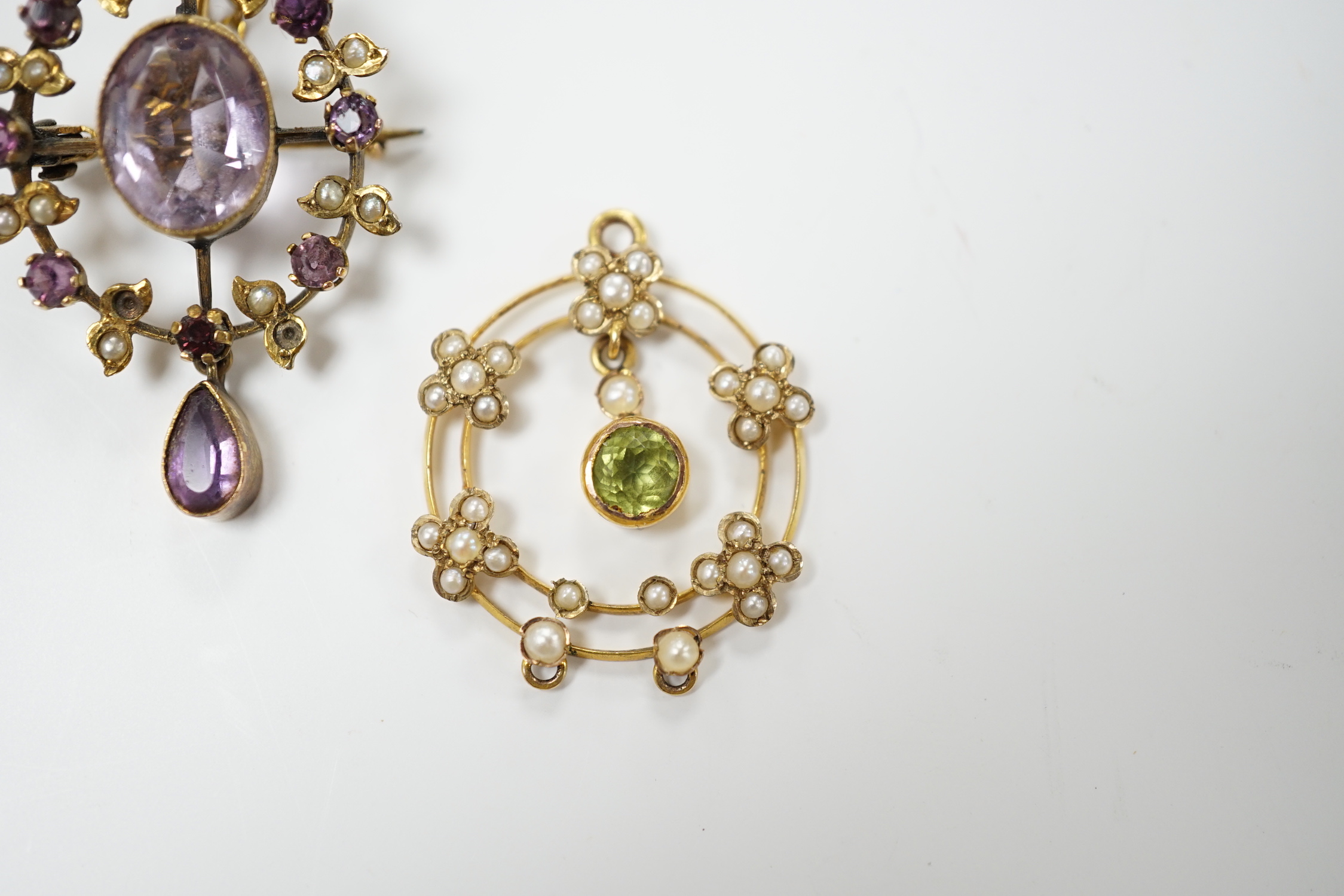 An early 20th century 9ct, peridot and seed pearl set drop pendant, 25mm and one other yellow metal and gem set pendant.